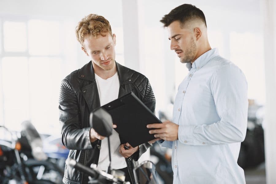 Twee mensen bespreken documenten naast een voertuig