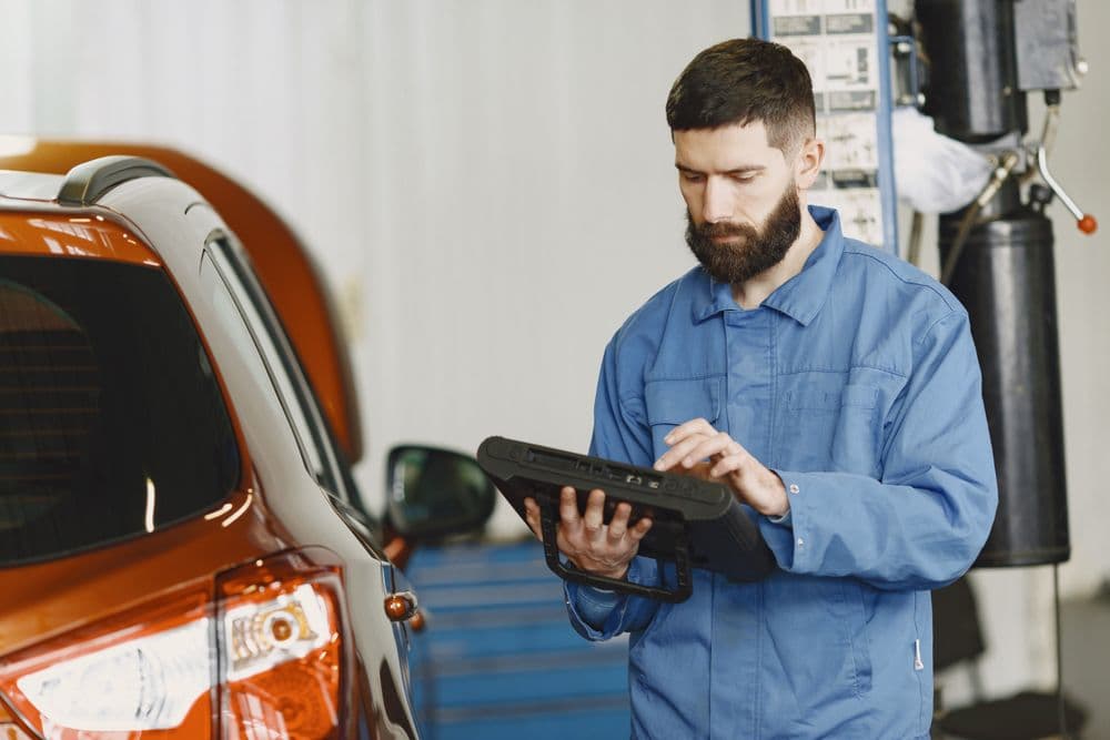 Monteur gebruikt een digitale diagnosetablet bij een auto (sfeerbeeld)